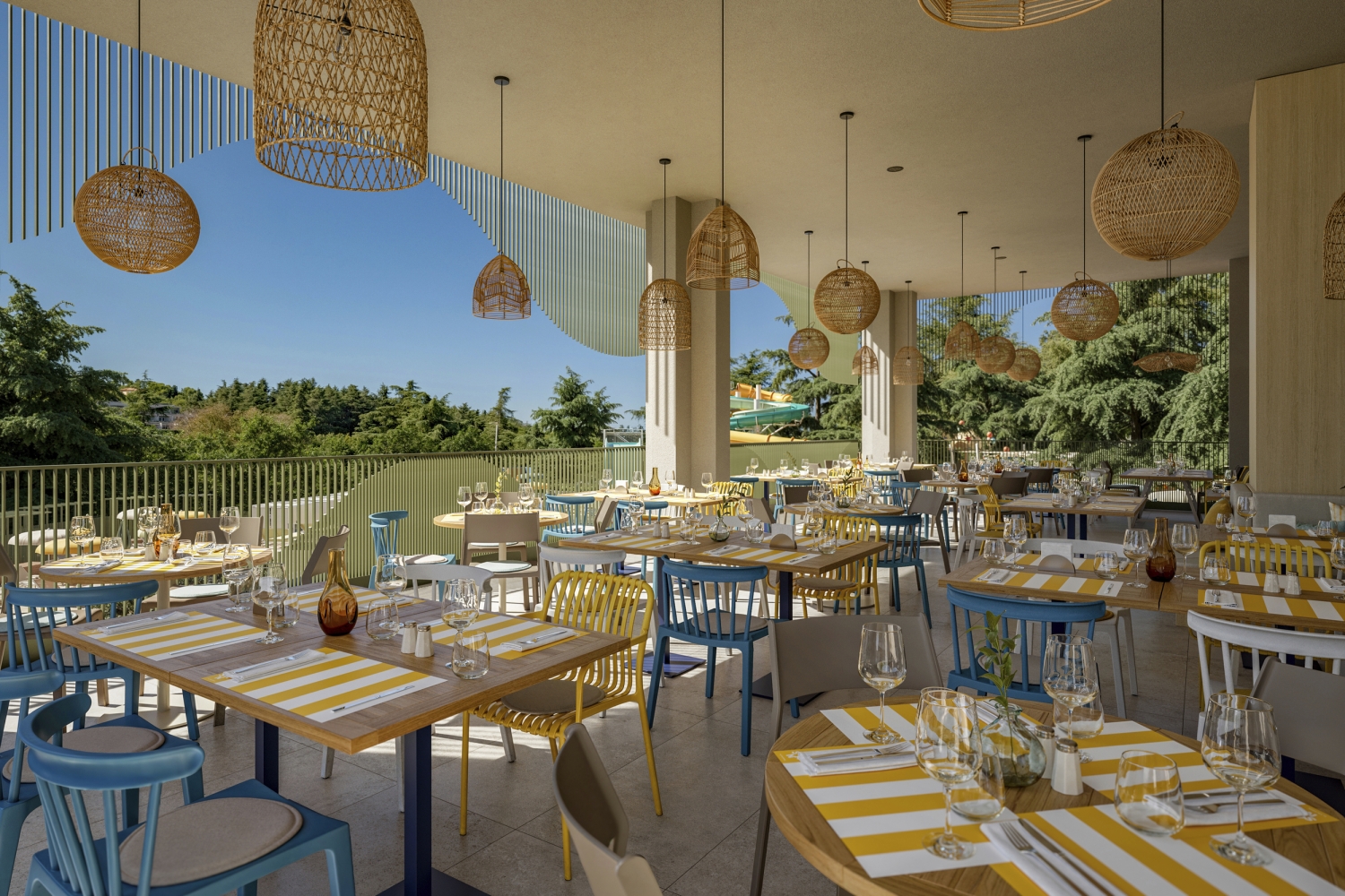 Terrasse eines Restaurants mit gelb-weiß gestreiften Tischtüchern und Blick ins Grüne.