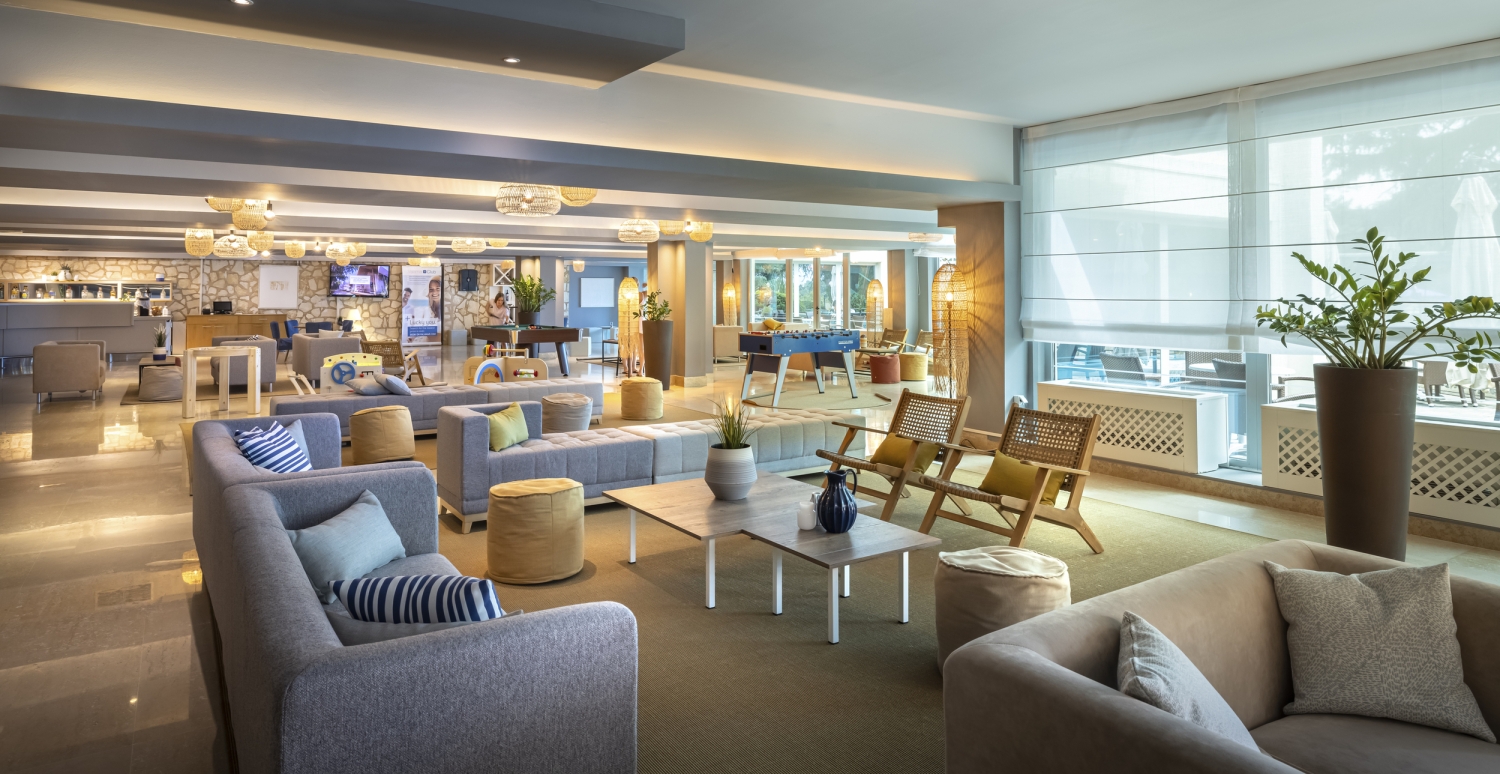Moderne Lounge mit Sofas und Sesseln, großen Fenstern und stilvollem Dekor.